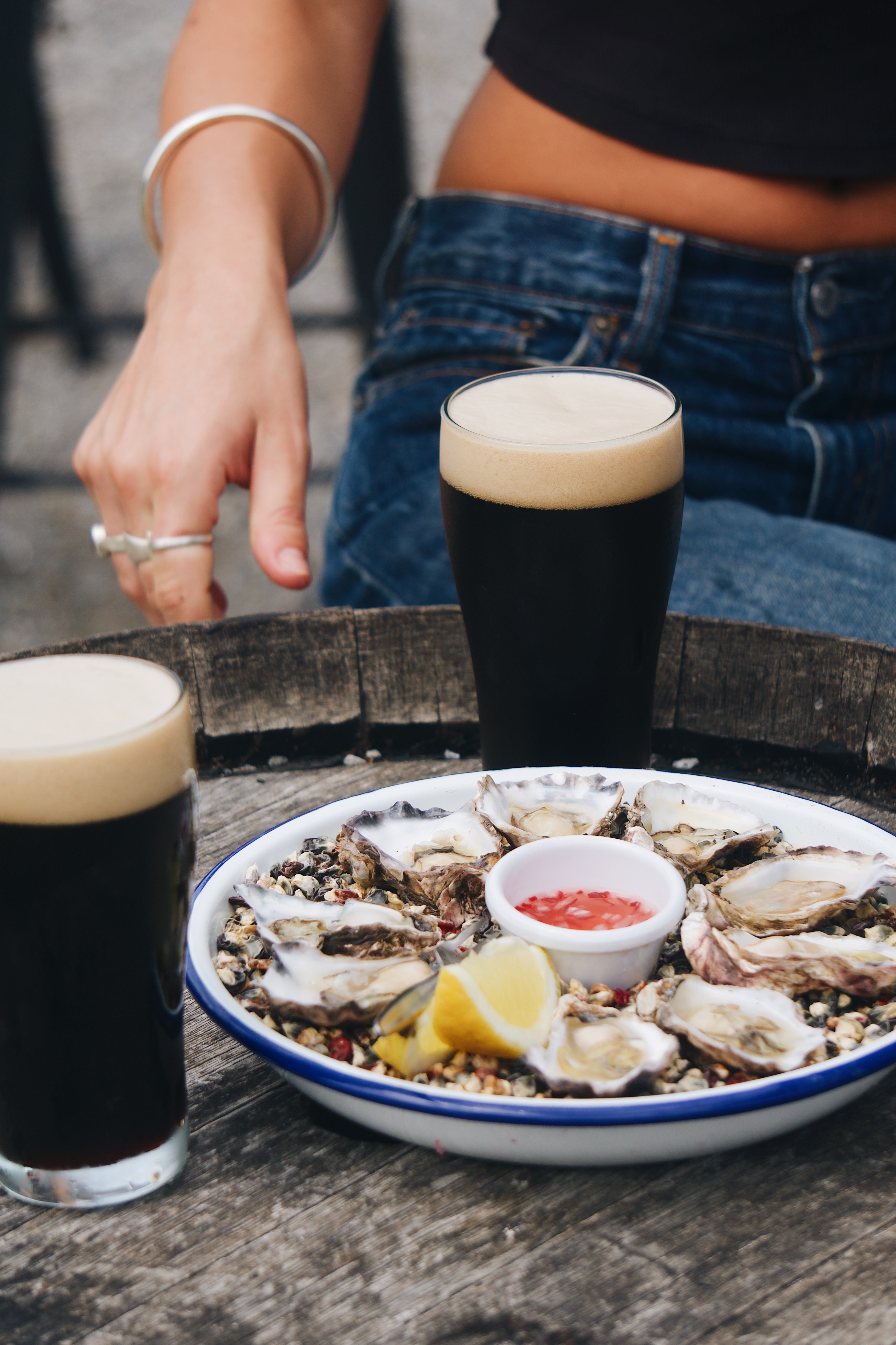 Person sitting at a table with oysters and dark beer at Sailors Grave Brewing Dunetown